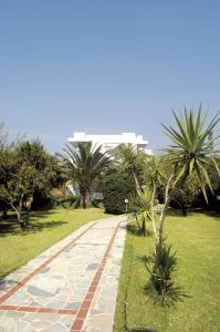 a walkway in a park with palm trees and a building at Proimos Apartments in Gerani