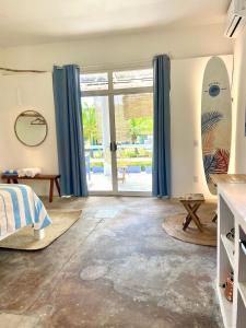 a bedroom with blue curtains and a surfboard on the wall at La Bocana Surf House in Santa Cruz Huatulco