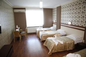 a hotel room with three beds and a table and chairs at Safir Hotels Silivri in Silivri