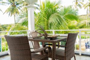 a table and chairs on a porch with palm trees at La Villa Allamanda in Rodrigues Island