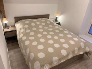 a bed with a polka dot cover in a room at Le Nalousie in Livry