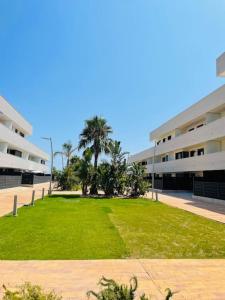 un prato davanti a un edificio con palme di Apartment- Roques Daurades Residential a L'Ametlla de Mar