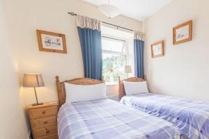 two beds in a small bedroom with a window at The Gallery Coniston in Coniston