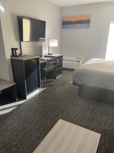 a hotel room with a bed and a desk with a television at Quality Suites in Abilene