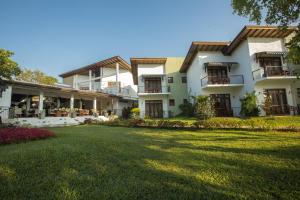 a building with a lawn in front of it at Sigiriya Wewa Addara Hotel - Hotel By The Lake in Sigiriya