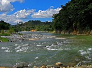 a river with rocks and trees in the background at Habitación Hogareña in Jarabacoa