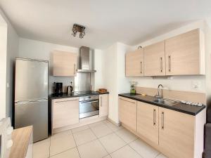 a kitchen with wooden cabinets and a stainless steel refrigerator at Au Fil De L'eau - Les Remparts in Dinan