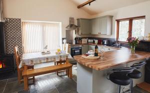 a kitchen with a table and a kitchen with a fireplace at The Old Dairy - Boutique Countryside Cottage at Harrys Cottages in Pen y Clawdd