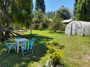 een tafel en stoelen in een tuin met een tent bij Hostel Casona Alameda in El Bolsón