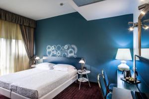 a bedroom with blue walls and a bed and a desk at Hotel Mirage in Florence