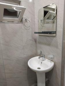 ein weißes Badezimmer mit einem Waschbecken und einem Spiegel in der Unterkunft My second home in Tbilisi City