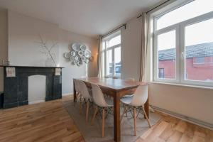 een eetkamer met een houten tafel en stoelen bij Appartement 4 chambres à Liège in Luik