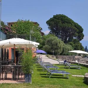 eine Reihe von Tischen und Stühlen mit Sonnenschirmen in der Unterkunft Bike Hotel Touring Gardone Riviera & Beach in Gardone Riviera