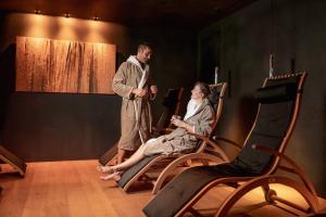 a man and a woman sitting on chairs on a stage at Stella Hotel - My Dolomites Experience in Selva di Val Gardena
