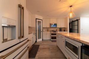 a kitchen with white cabinets and a wooden floor at Modern San Pedro Home Sleeps 12 in San Pedro