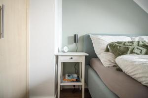 een bed met een nachtkastje naast een tafel met een klok erop bij nJoy! Sonnig & Zentral - Queensize - Kaffee - Netflix - Balkon - perfekt für Business & Paare in Neckarsulm +25 foto's