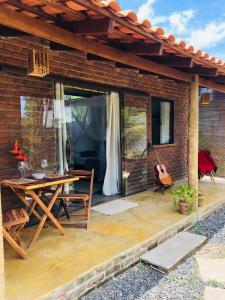 eine Terrasse mit einem Holztisch und einer Gitarre in der Unterkunft Aruanã - Praia do Sargi in Serra Grande