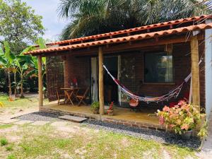 une petite maison avec un hamac en face de celle-ci dans l'établissement Aruanã - Praia do Sargi, à Serra Grande