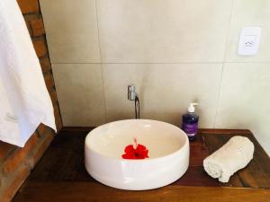 una vasca da bagno bianca con un fiore rosso di Aruanã - Praia do Sargi a Serra Grande