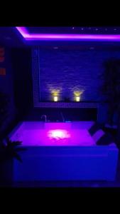 ciemny pokój z wanną z fioletowymi światłami w obiekcie Spa Apartment w Belgradzie