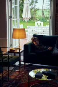 a woman laying on a couch in a living room at Historisches Bauernhaus Fehmarn in Strukkamp auf Fehmarn +38 photos