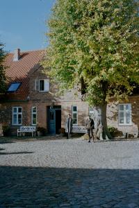 duas pessoas em frente a um edifício com uma árvore em Historisches Bauernhaus Fehmarn em Strukkamp auf Fehmarn