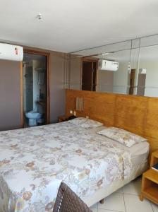 1 dormitorio con 1 cama grande y espejo en Flat Suite Natal, en Natal
