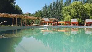 a pool of water with tables and chairs and trees at Domos Uspallata in Uspallata