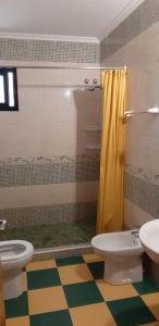 baño con 2 aseos y cortina de ducha amarilla en Cortijo Los Conquistadores en Lucena del Puerto