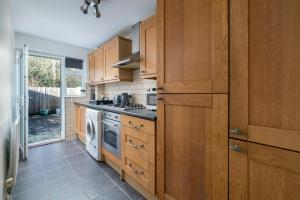 a kitchen with wooden cabinets and a washer and dryer at Crawley 1-Bedroom Pet Friendly Apartment in Three Bridges