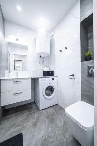 a white bathroom with a washing machine and a sink at Apartment Le Château in Radom