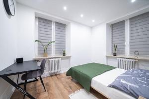 een slaapkamer met een bed, een bureau en ramen bij Apartment Le Château in Radom