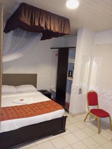 1 dormitorio con 1 cama y 1 silla roja en Beach View Hotel - Kisumu en Kisumu