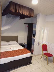 - une chambre avec un lit et une chaise rouge dans l'établissement Beach View Hotel - Kisumu, à Kisumu