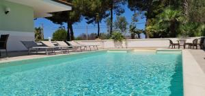een zwembad met stoelen en een tafel en een zwembad bij Villa Vimade con Piscina Privata in Marina di Mancaversa