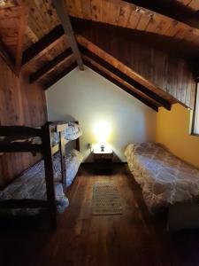 a bedroom with two beds and a lamp in a attic at Hostel Casona Alameda in El Bolsón