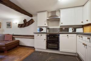 a kitchen with white cabinets and a stove top oven at The Mountain Cottages - Millrace in Coniston