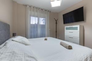 a bedroom with a white bed with a tv on the wall at Chalet Tiro del Pichón I in Marbella