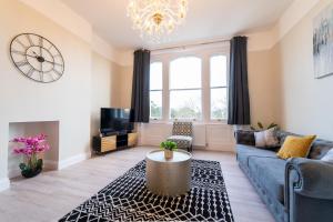 a living room with a blue couch and a clock at Stylish maisonette in town centre close to beach in Great Yarmouth