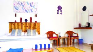 een slaapkamer met een bed en 2 stoelen en een tafel bij Modara Ocean Villa in Tangalle