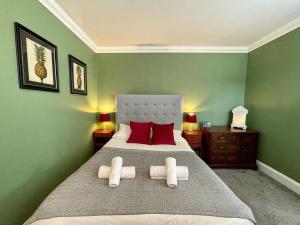 a green bedroom with a large bed with red pillows at Regency Apartment - Marine Square By Crown Gardens Holiday Homes in Brighton & Hove