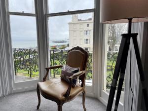 una silla sentada en una habitación con ventana en Regency Apartment - Marine Square By Crown Gardens Holiday Homes, en Brighton & Hove