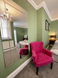 a bedroom with a pink chair and a mirror at Regency Apartment - Marine Square By Crown Gardens Holiday Homes in Brighton & Hove