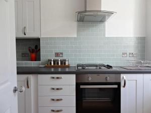 cocina con armarios blancos y fogones en Regency Apartment - Marine Square By Crown Gardens Holiday Homes, en Brighton & Hove