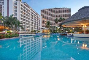 a large swimming pool in a resort with buildings at Beachfront Resort Condo beside la Isla Mall in Puerto Vallarta
