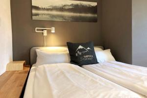 un letto bianco con un cuscino sopra di Wohnung mit Balkon in Velden - Appartment BERGE byTILLY a Velden am Wörthersee