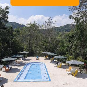 a swimming pool with chairs and umbrellas on a beach at Finca Pozo Azul in La Vega