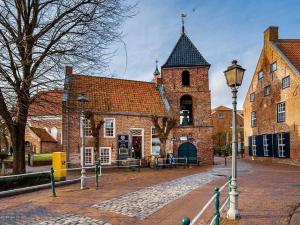 ein altes Backsteingebäude mit einem Uhrturm in der Unterkunft Ferienhaus Gretel  in Greetsiel