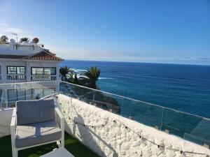 a white chair sitting on a balcony overlooking the ocean at Infinity View in Puerto de la Cruz