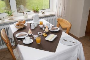 a dining room table with a white table cloth and food at Pension Sielmöwe in Neuharlingersiel